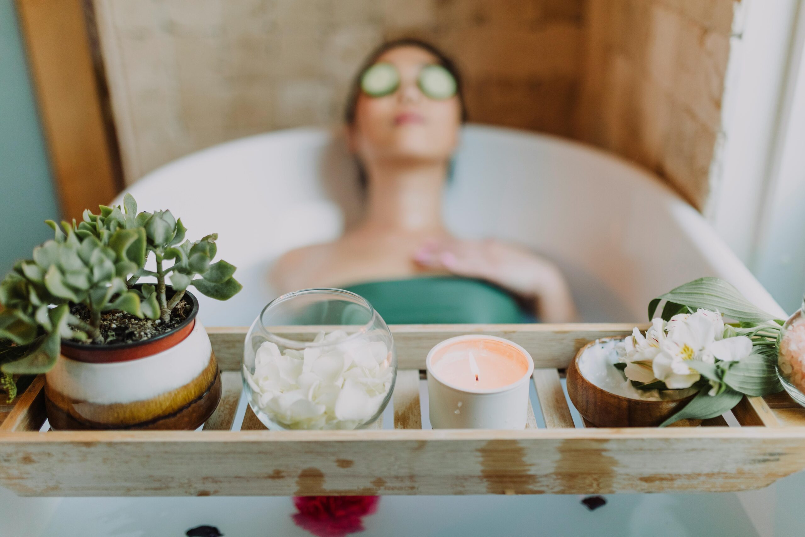 Skincare essentials 30's lifestyle beauty fashion blog Woman relaxing in a bathtub with a candle and plants, enjoying a serene spa experience.